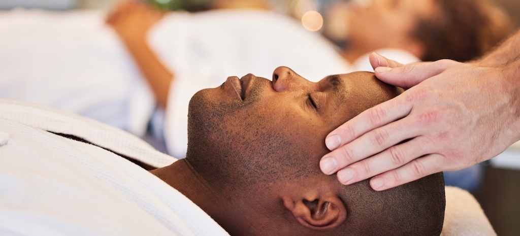 Black man, relax and head massage with therapist hands in a luxury spa, wellness and skincare during rehab