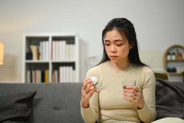 Upset young woman reading medicine instruction on adderall controlled substance packaging. Healthcare, medication concept.