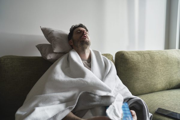 Ill man sitting under the blanket